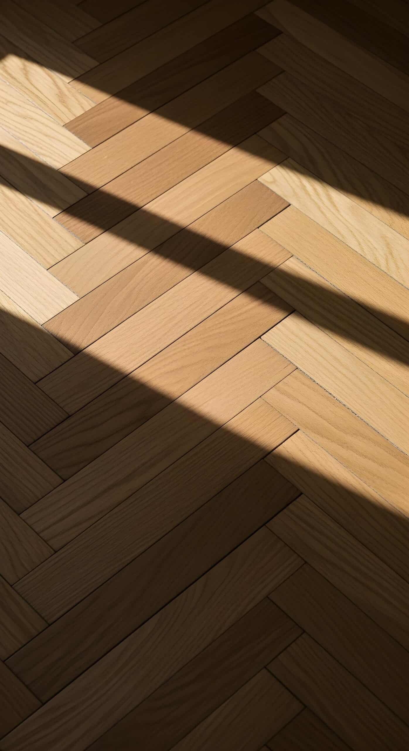 Close-up of herringbone wood flooring pattern with natural light and warm finish.