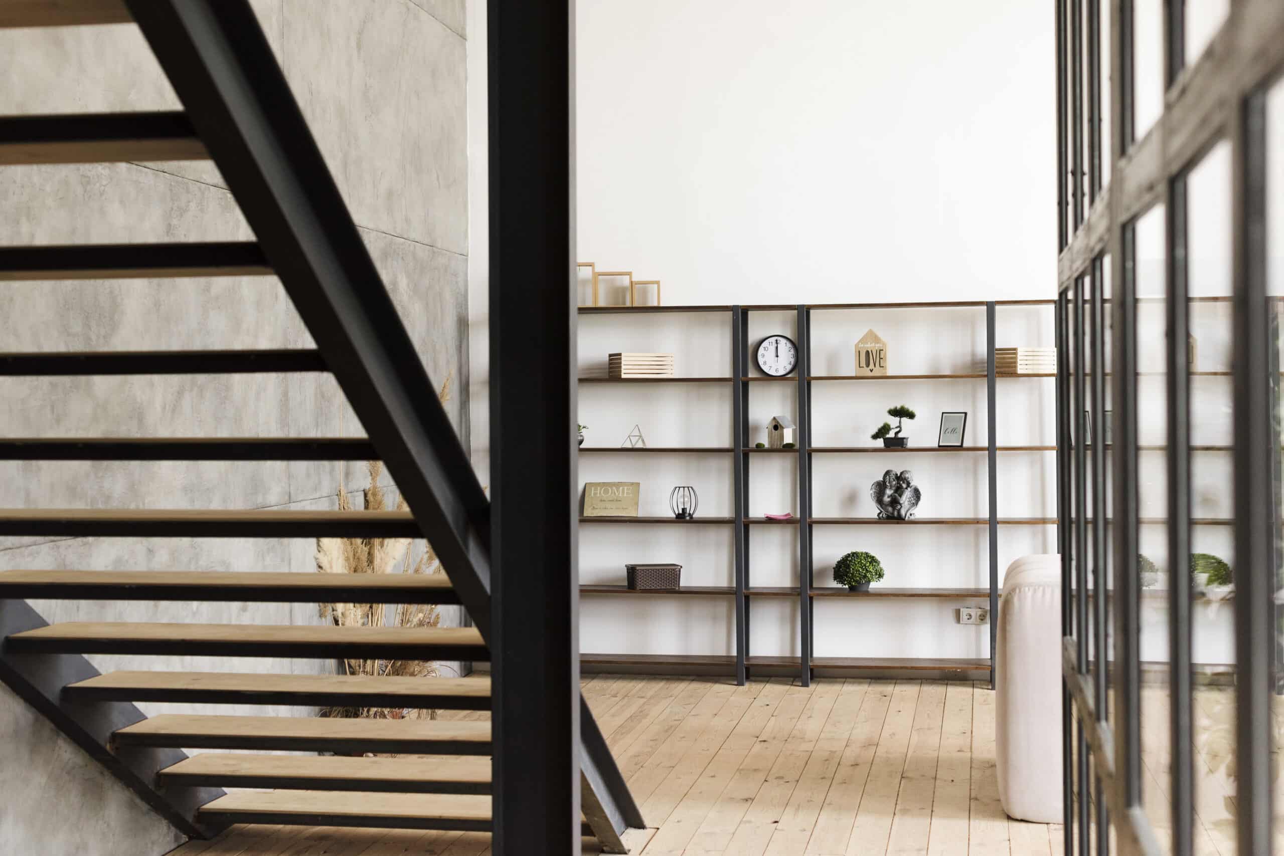Contemporary basement with open wood staircase, industrial metal frame, and custom shelving unit.
