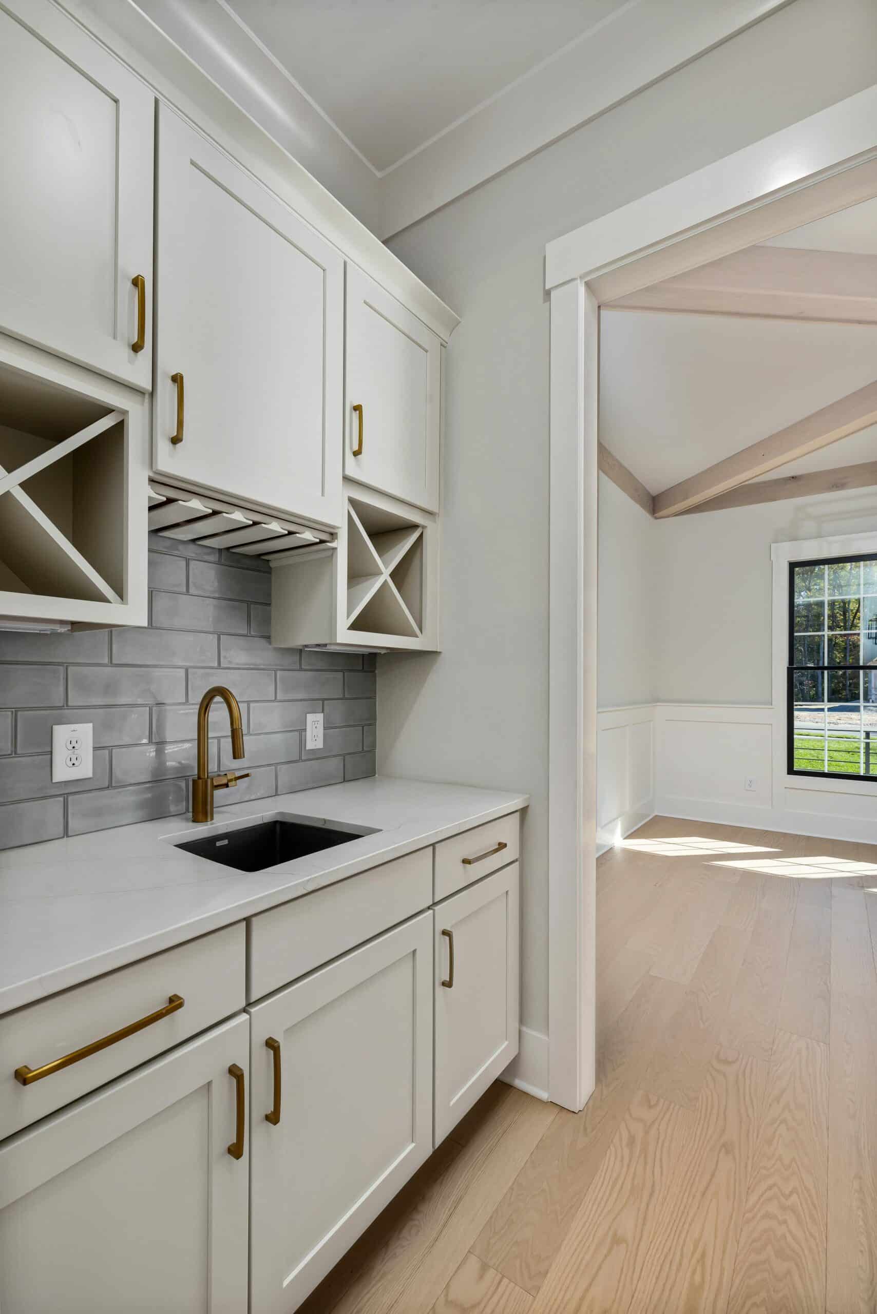Bright kitchen with custom white cabinetry, gold hardware, and gray subway tile backsplash.
