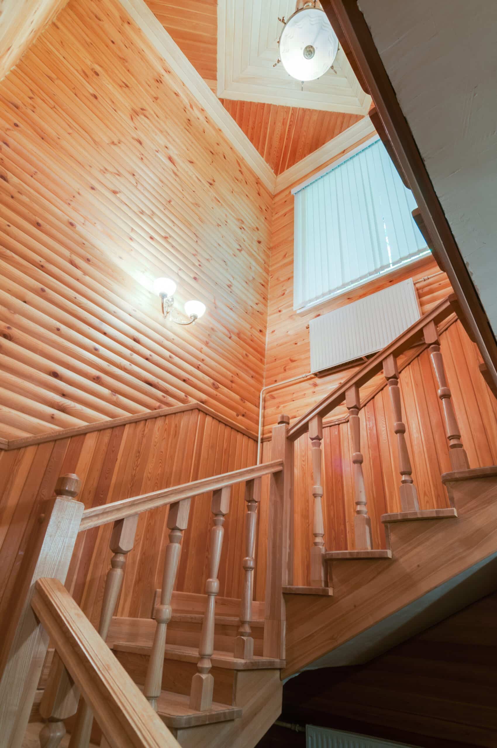 Wood staircase with matching wall paneling and natural finish in a remodeled basement.